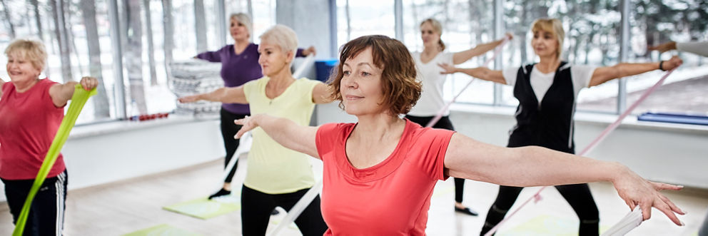 A group of older women smile as they participate in an exercise class