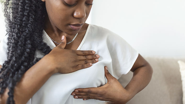 A woman performs a breast self-exam at home