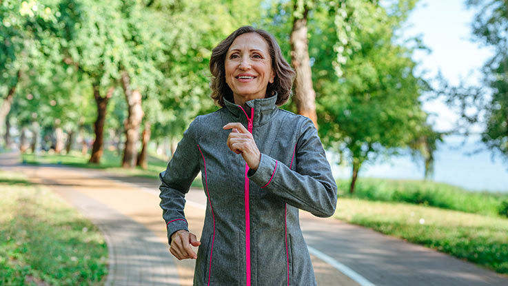 A woman jogging outside next to a lake.