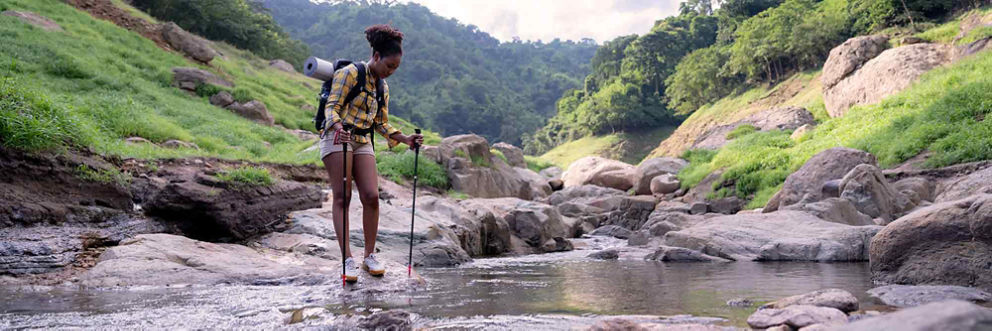 A woman crosses a stream during a hike.