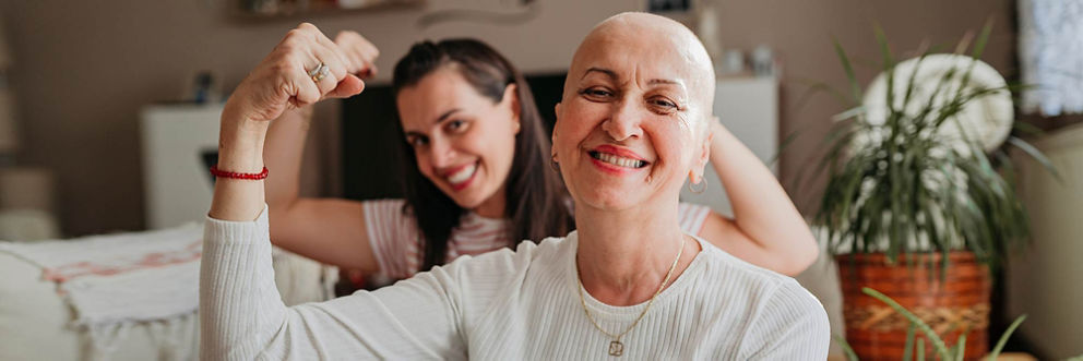 A cancer patient and her daughter smile and flex their muscles. 