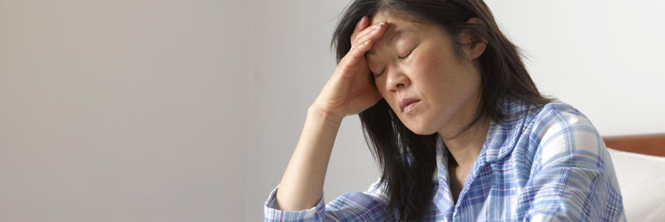 A woman with her hand on her forehead to relieve headache pain. 