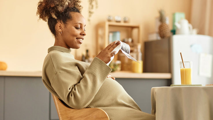 Sitting at her kitchen table, a young pregnant woman smiles at images of her ultrasound.