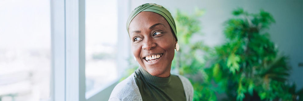 A woman with a head scarf smiles while looking out the window.