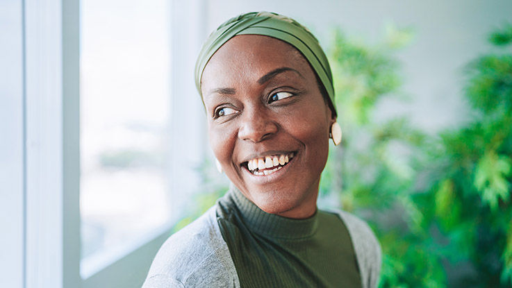 A woman with a head scarf smiles while looking out the window.