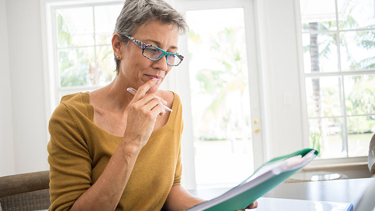 A volunteer reviews a list with her reading glasses on and a pen in her hand.