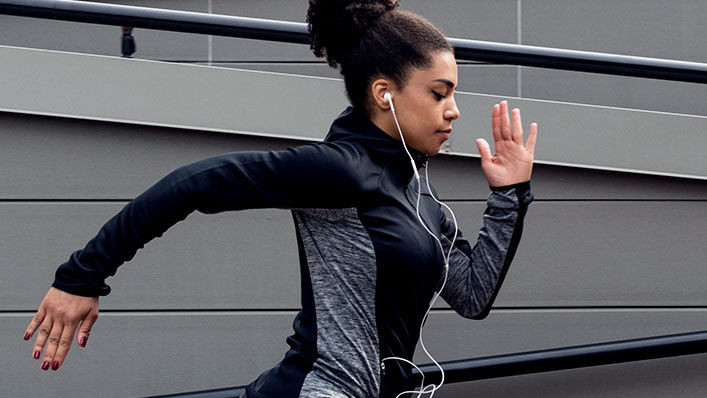 Young African American woman in a running stride outdoors.