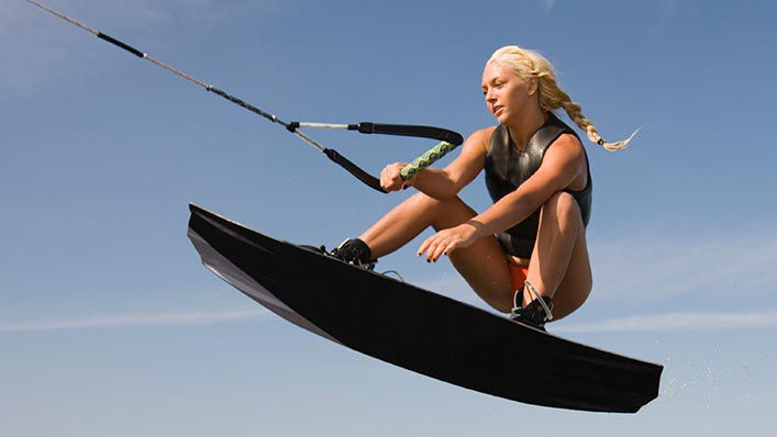  A female wakeboarder leans back as she hovers over the water in mid-air.