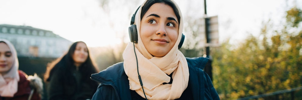 A woman wearing headphones and listening to music on her walk with friends