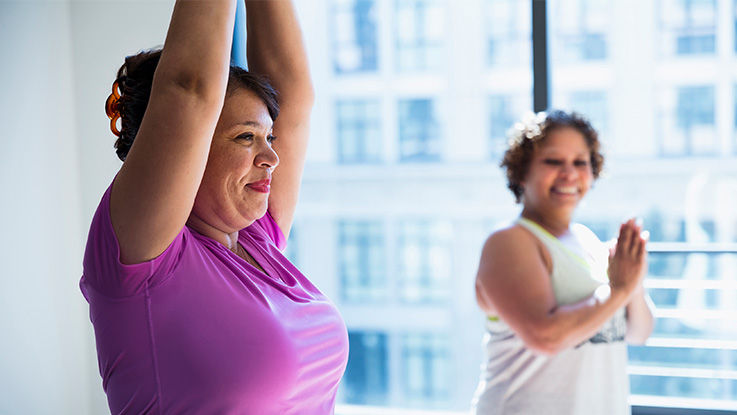 A woman encourages her friend during a yoga session.
