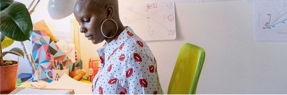 Woman with large hoop earrings and a printed top works at her desk