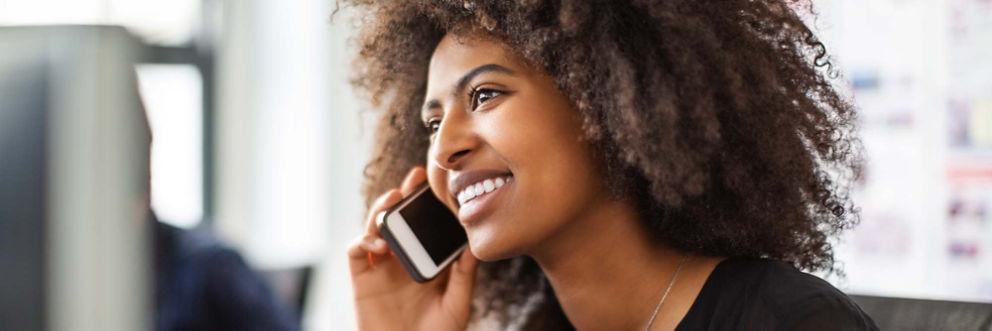A woman smiles as she speaks to someone on her phone