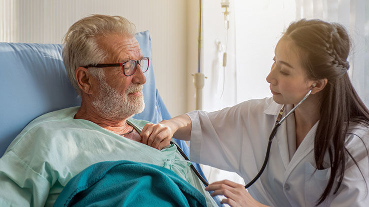 A nurse presses a stethoscope to an older man’s chest.