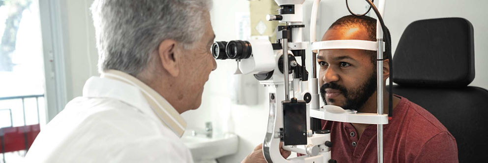 A doctor examines a man's eyes through a machine.