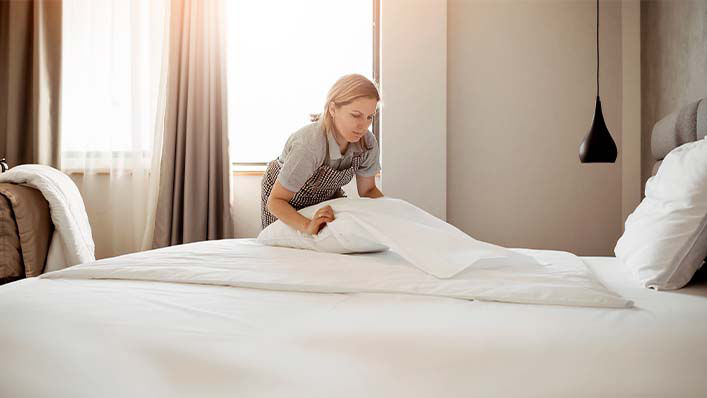 A woman conducts routine housekeeping in a hotel room.