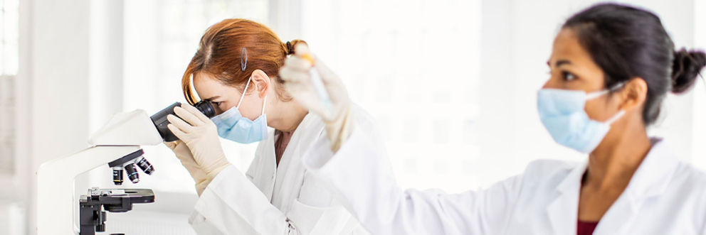Two women examine samples in a lab.