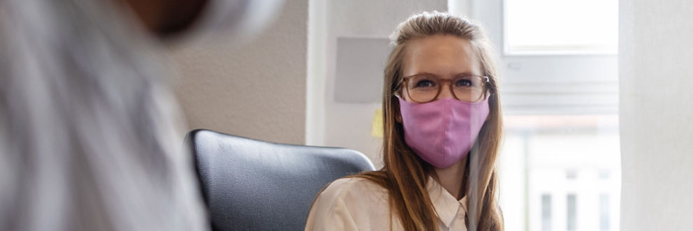A young woman wears a mask at her office.