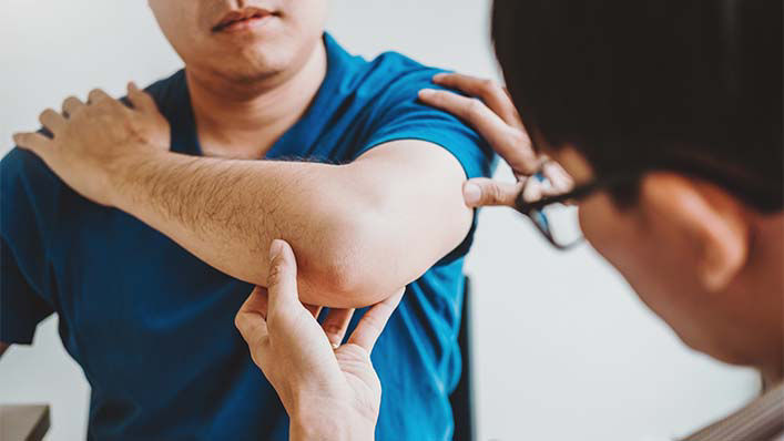 A doctor examines a man's elbow.
