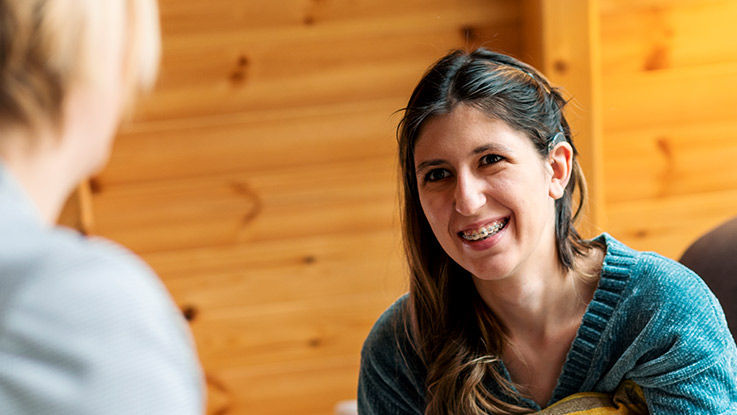 A woman with braces and a cochlear implant smiles up at her care provider.