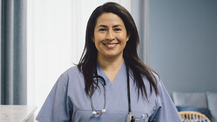 A nurse wearing scrubs and a stethoscope smiles in her headshot. 