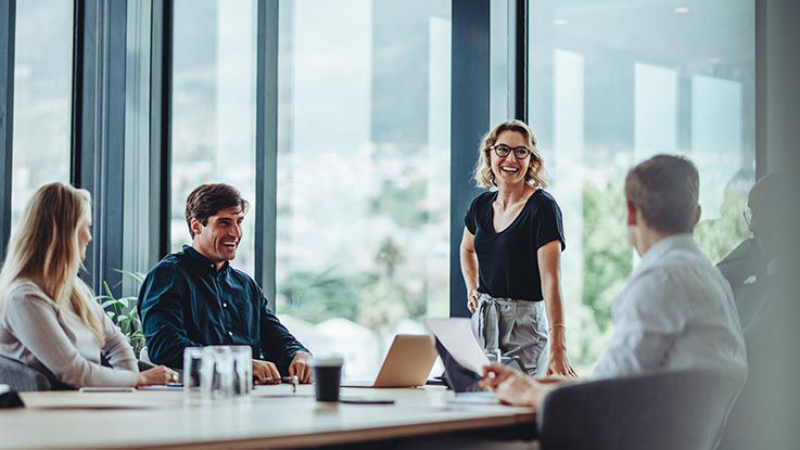 A woman smiles as she leads a meeting in a conference room