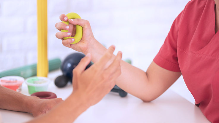 A patient squeezes a device in their hand in order to strengthen their hand and wrist. 