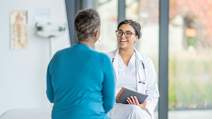 A smiling doctor talks to a patient about their hernia treatment options.