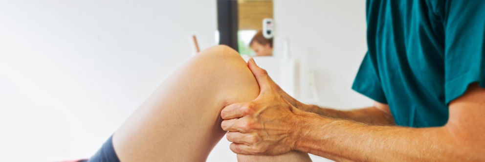 A physical therapist examines a patient's knee.