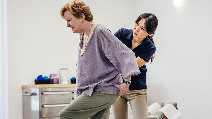 A doctor performs a physical exam on her patient's lower back.
