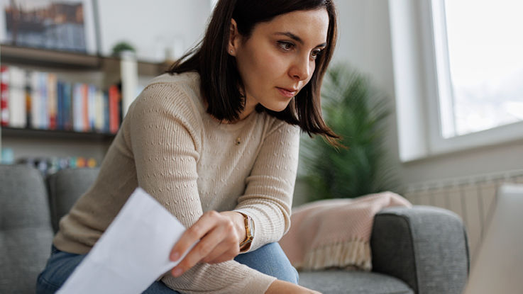 A woman carefully reviews information on her laptop as she works from home