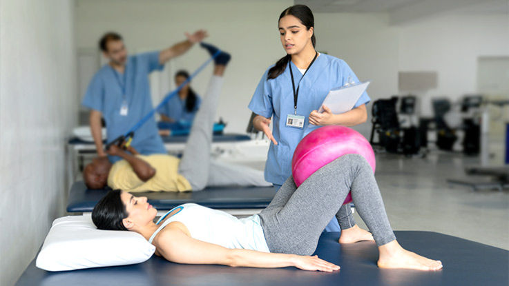 A physical therapist guides her patient through an exercise that strengthens the pelvic floor. 