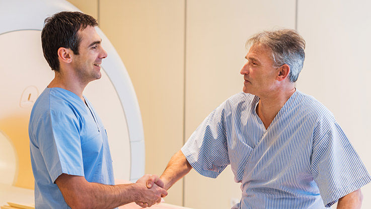 A cancer patient shakes hands with their oncologist after receiving radiation therapy. 