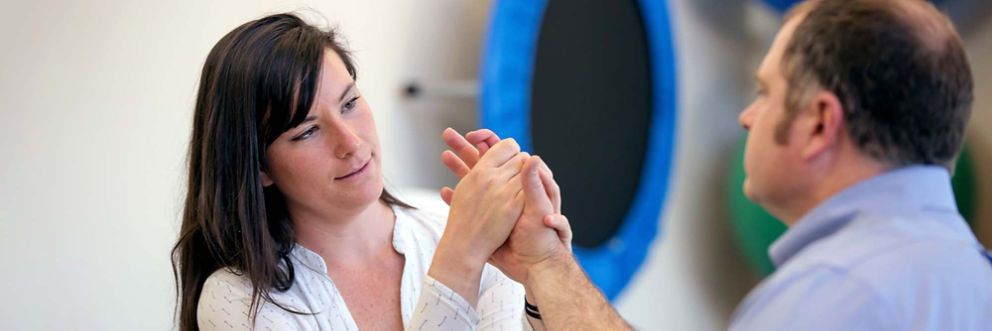 A physical therapist examines a patient's hand.