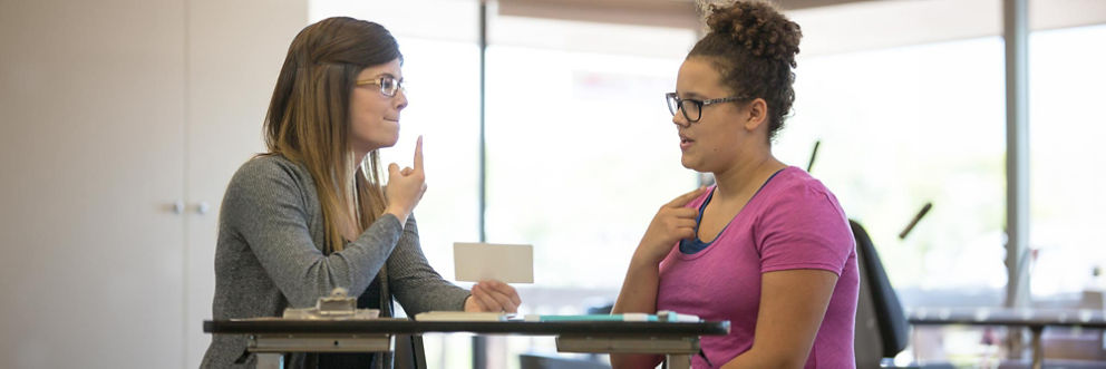 Speech therapist works with a patient by tapping her mouth with her index finger.