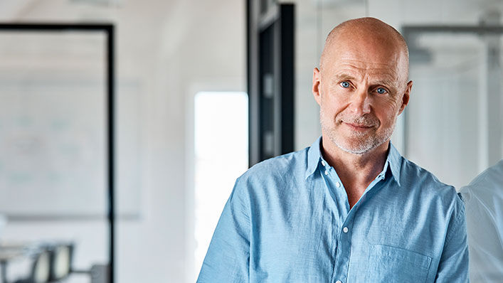 A man in business attire looks thoughtfully at the camera