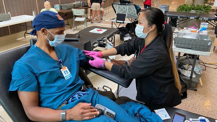A nurse prepares materials as a doctor sits in the chair next to her waiting to give blood.