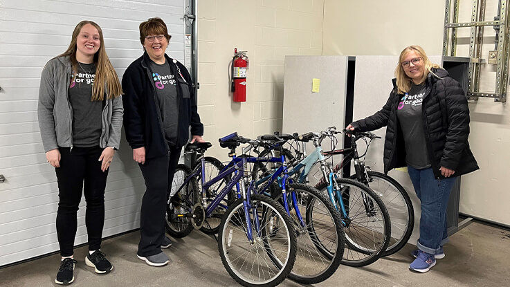 Volunteers pose for a photo standing next to a row of donated bikes.