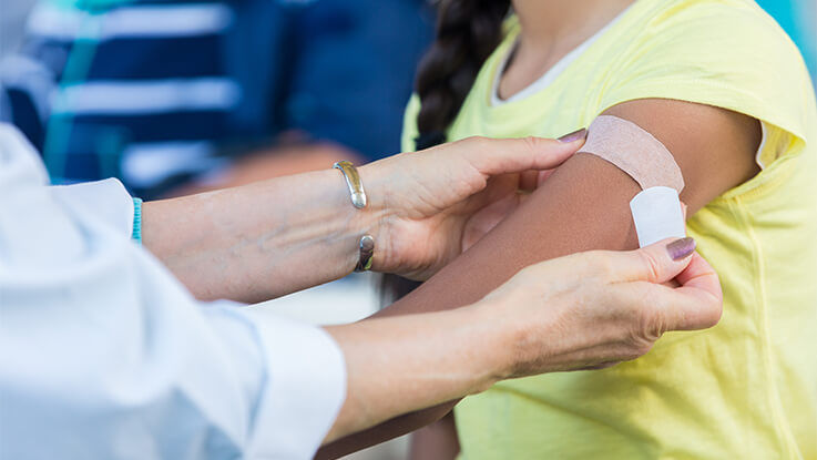 A doctor places a Band-Aid on a child's arm after giving them a vaccine shot.