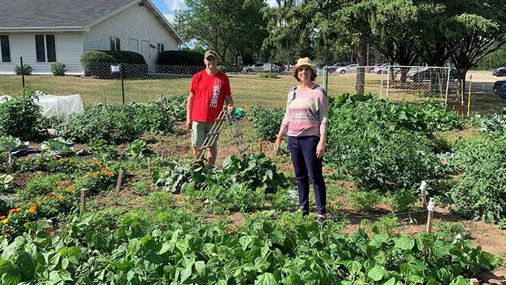 Two residents pose for a photo in their thriving community garden.