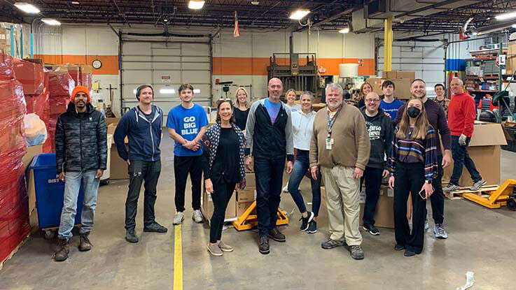 A group of people stands in a warehouse with donated goods.