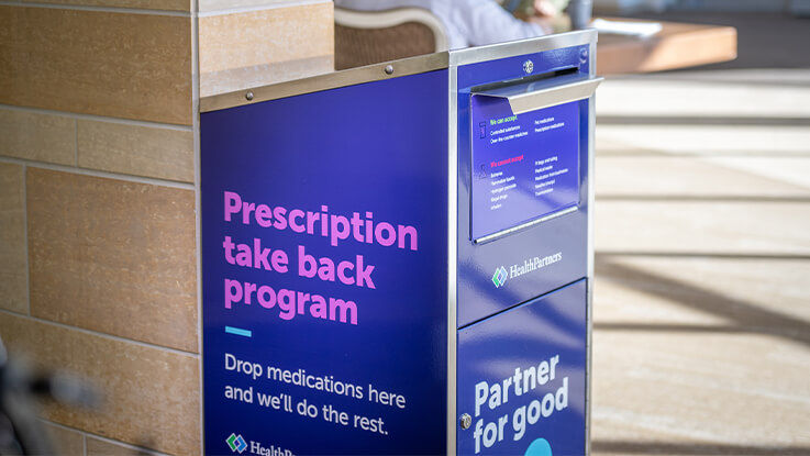 A metal receptacle labeled Prescription take back program sits in a HealthPartners hospital hallway.