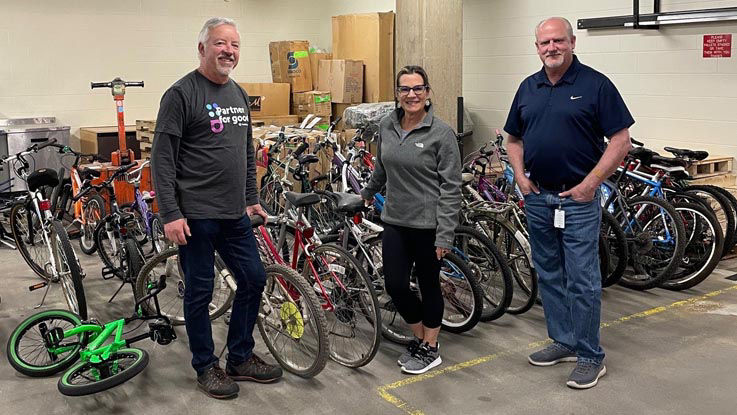 HealthPartners team members stand with bike shop employees in front of several bikes.