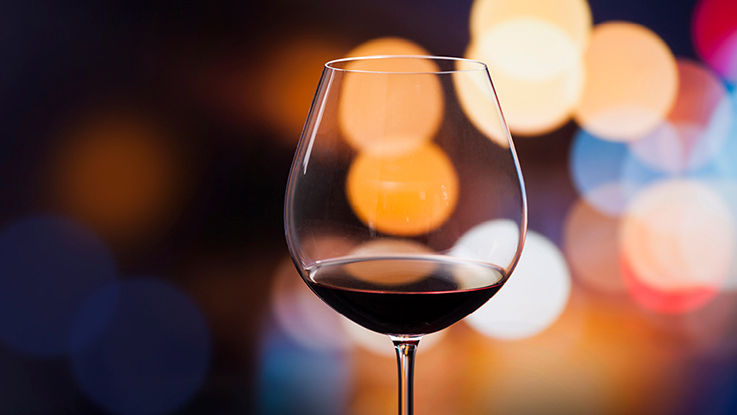 A wine glass with a background of out multicolored lights.