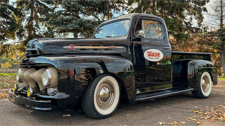 An antique black pickup truck bears the Blaze Credit Union logo on its cab door.