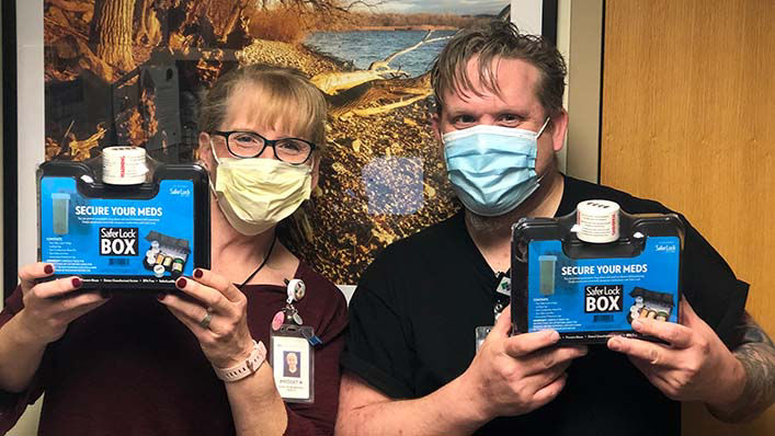 Two employees holding a medication lock box.