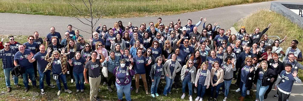 A large group of people wearing Make Good Happen shirts pose for a photo after an event.