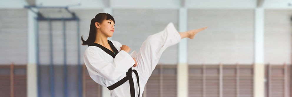 A young woman practices a karate kick.