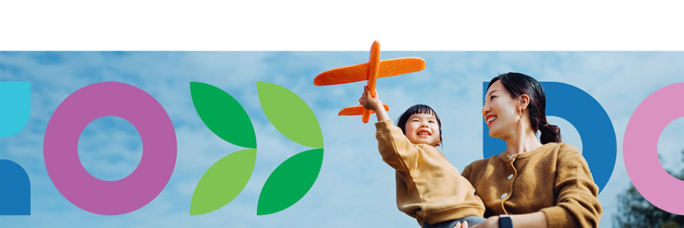A mother holding their child while she plays with a model plane. The HealthPartners logo is in the background.